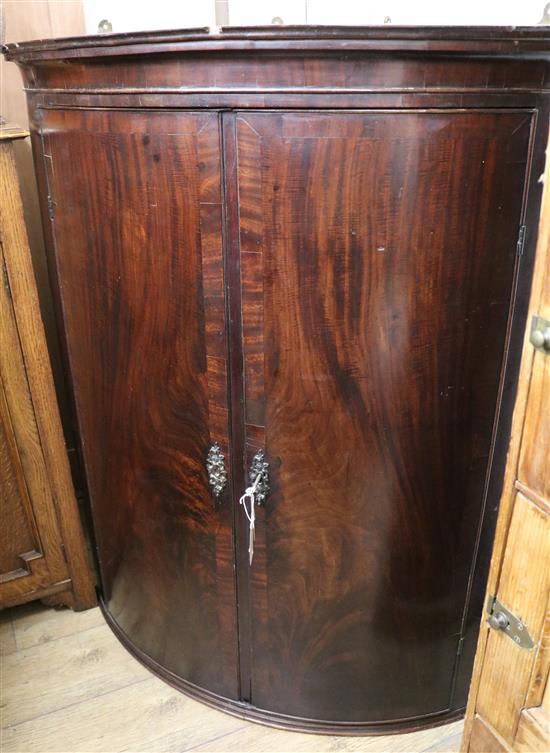 A Regency mahogany bowfront corner cupboard W.99cm